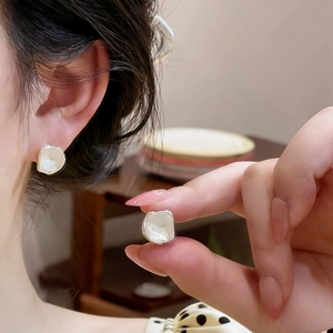 Close-up of irregular square glass stud earrings in minimalist design.