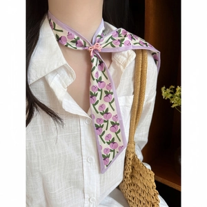 Close-up of floral tulip pattern silk scarf necklace with adjustable buckle on a model.