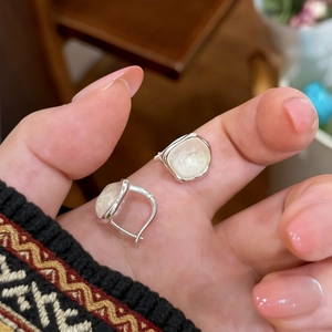 Close-up of irregular square glass earrings held by fingers showing fine silver finish