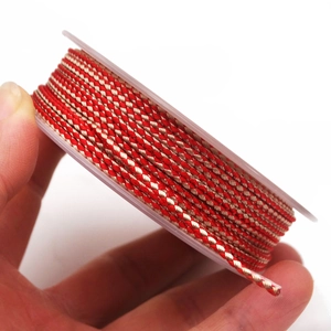Detail of red and gold braided dragon pattern cord on a spool for DIY jewelry making