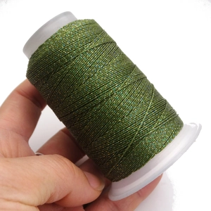Dettaglio macro del cordoncino cerato verde scuro su bobina per intrecciare gioielli