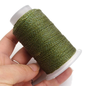 Dettaglio del cordoncino cerato verde scuro con glitter su rocchetto per gioielli fai-da-te