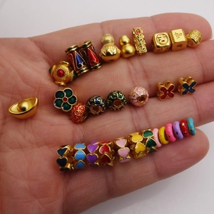 Handheld assortment of gold-plated enamel beads including heart and gourd shapes
