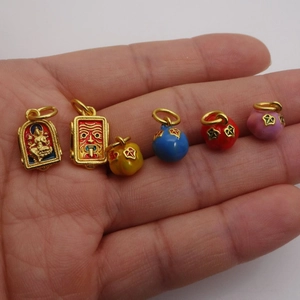 Pendentifs en émail doré de style traditionnel tenus en main pour illustrer la taille