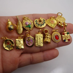 Collection of thirteen assorted gold-tone enamel pendants and traditional charms in hand