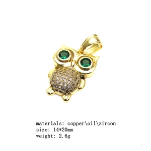 Detail of gold-plated copper owl pendant with green and white zircon stones, size 14x20mm