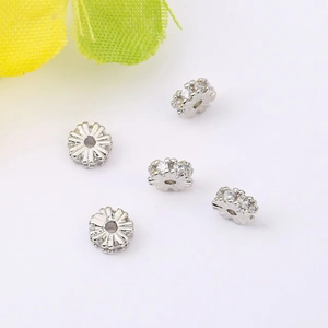 Close-up of 5 silver flower-shaped spacer beads with micro-set crystals for jewelry making