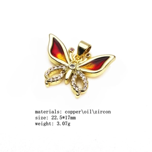 Macro view of copper butterfly pendant with orange enamel and zircon inlays