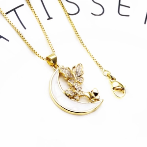 Macro shot of gold-plated crescent moon and butterfly pendant with sparkling cubic zirconia
