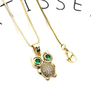 Macro shot of owl pendant with green gemstone eyes and white cubic zirconia crystals