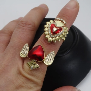 Adjustable golden rings with red heart zircon and sacred heart design on woman's hand