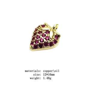 Detail view of a red strawberry pendant charm made of copper with oil dripping and red stones