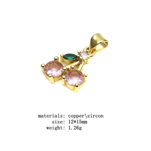Macro detail of cherry pendant in gold plated copper with pink and green zircon stones