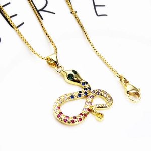 Dettaglio macro del ciondolo a serpente dorato con zirconi colorati e catena a scatola