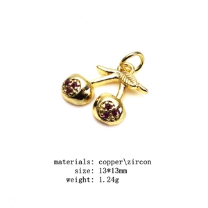 Detail shot of a copper cherry pendant with red zircon and golden leaves 13x13mm