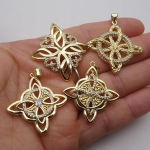 Gold Celtic knot pendants with white zircon inlays shown held in hand for size reference