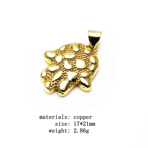 Macro-opname van vergulde koperen Hamsa-hanger met unieke metalen textuurafwerking