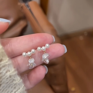 Close-up detail of elegant pearl and sparkling zircon tassel stud earrings for women