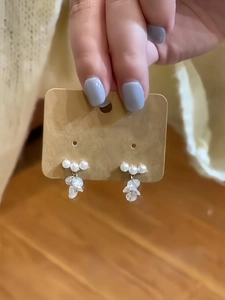 Close-up of elegant pearl and zircon drop earrings on kraft paper card presentation