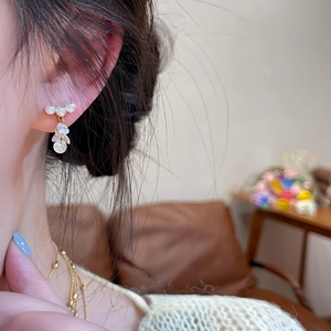 Detail of elegant pearl and zircon tassel stud earrings on ear for a sophisticated look