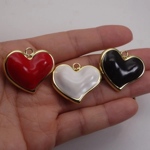 Handheld view of colorful enamel heart pendants with gold plating for jewelry making