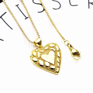 Macro-opname van gouden hart hanger met matte textuur en karabijnsluiting aan box ketting