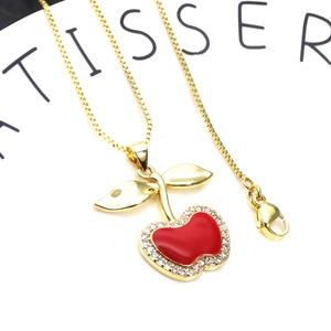 Macro shot of gold-plated cherry pendant with red enamel and pavé zircon stones