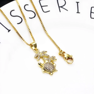 Detail of gold-plated box chain with turtle and palm tree zircon pendants and lobster clasp