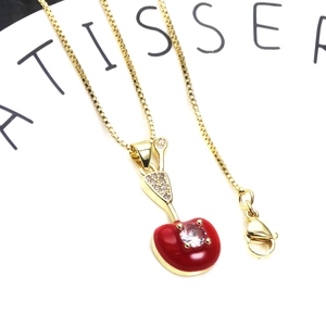 Detailed macro view of cherry pendant necklace with red enamel and pavé cubic zirconia
