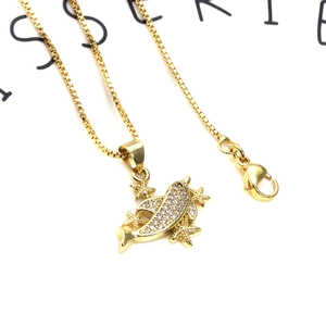 Macro detail of gold plated box chain with dolphin and starfish pendants set in zircons