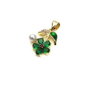 Detailed macro view of a gold flower pendant with green petals and a white pearl