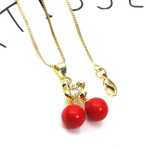 Close-up of red cherry pendant with gold leaves and cubic zirconia on box chain