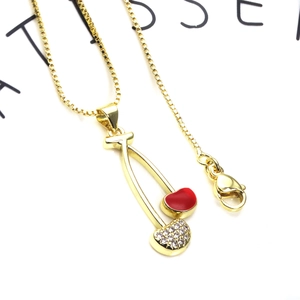 Macro shot of gold box chain with red enamel cherry pendant and sparkling zircon stones