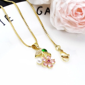 Gold flower necklace with pink stones, green leaves and a white pearl on a box chain