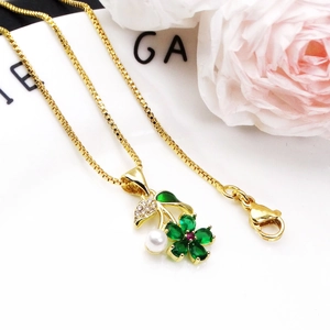 Detail of gold flower necklace with green petals, a pink zircon center and a white pearl