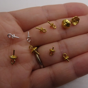 Handheld view of gold and silver plated copper water drop pearl caps for DIY jewelry