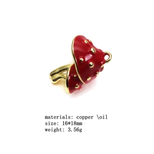 Macro view of red mushroom charm pendant in gold plated copper with oil drop detail