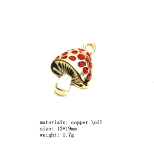 Macro view of mushroom pendant charm with red oil drop design and copper gold finish