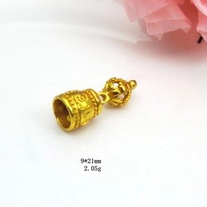 Macro detail of a 9x21mm gold plated Vajra bell pendant with Buddhist carvings