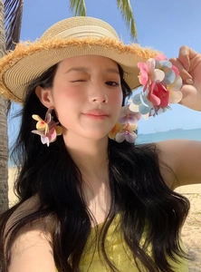 Close-up of vibrant colorful floral C-shaped earrings on a model at the beach
