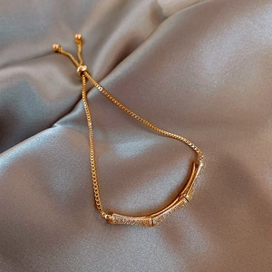Detailed view of a gold bamboo-joint bracelet with sparkling stones on silk fabric.