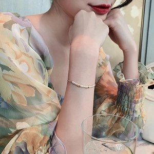 Elegant gold bamboo-style bracelet with pave stones shown on a model's wrist in a lifestyle setting.
