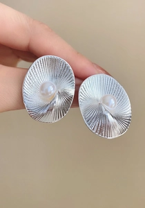 Dettaglio macro di orecchini a spirale in argento vintage con eleganti perle centrali