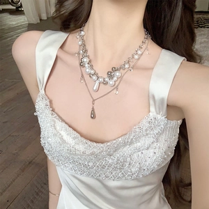 Close-up of elegant multi-layer pearl necklace with silver-tone beads and teardrop pendants.