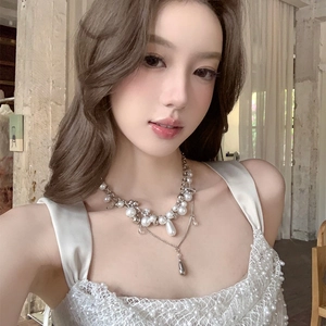 Elegant multi-layer pearl necklace with a metallic teardrop pendant worn by model