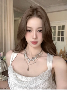 Elegant multi-layered white pearl necklace with silver pendants worn by Asian model