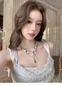 Detailed view of an elegant multi-layer pearl necklace on a model wearing white lace