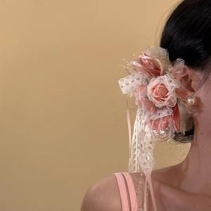 Vue détaillée d'une barrette à fleurs roses douces avec dentelle et perles délicates.