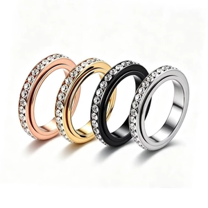 Detailed view of four stainless steel spinner rings in various colors with sparkling crystals.