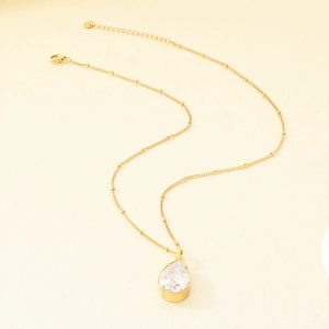 Primo piano di un elegante collana in oro acciaio con ciondolo a goccia in cristallo